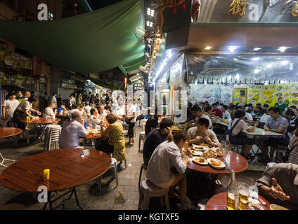 HONG KONG, CHINA - JUNE 16, 2017: Tourists and local dine in a restaurant in the streets of Kowloon near the famous Temple night market in Hong Kong. Stock Photo