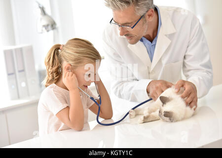 Little girl at the vet with her cat, listening to its heartbeat Stock Photo