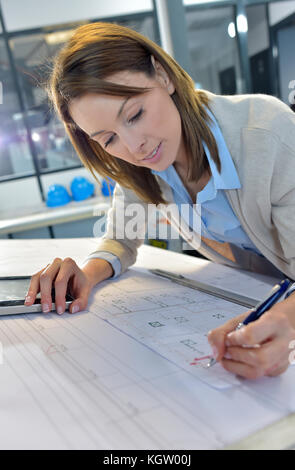Woman engineer working on blueprint in office Stock Photo