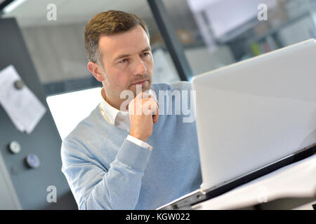 Industrial manager in office working on laptop Stock Photo
