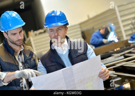 Engineer with mechanical worker checking on production Stock Photo