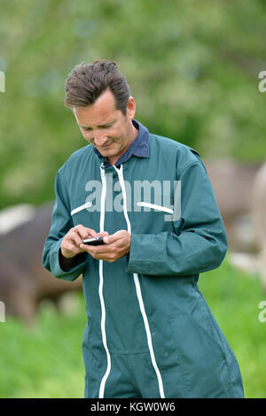 Farmer with overall sending message with smartphone Stock Photo
