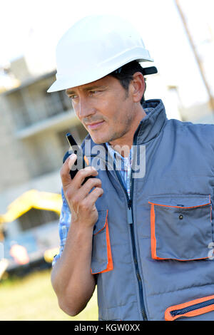 Man on building site using walkie-talkie Stock Photo