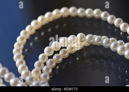 String of beautiful cultured pearls with dark blue and black abstract background Stock Photo