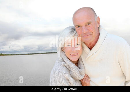 Portrait of happy senior couple standing by a lake Stock Photo