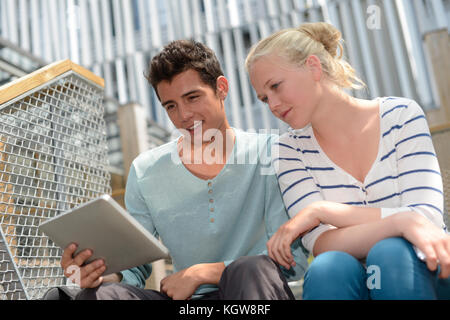 Students in school yard using digital tablet Stock Photo