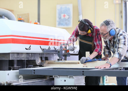 Young trainee in carpentry using sawing machine Stock Photo
