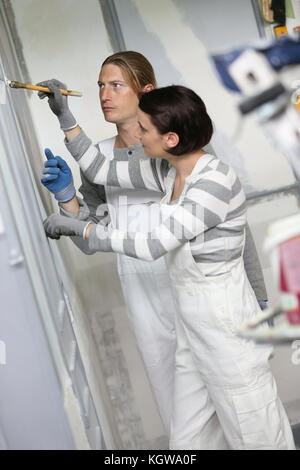 Young woman painter in professional training, teacher controlling work Stock Photo
