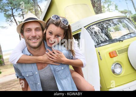 Cheerful couple standing in front of camper van Stock Photo