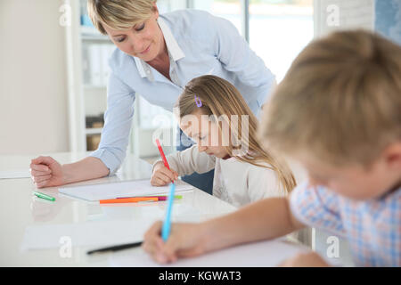 Teacher helping kids in classroom Stock Photo