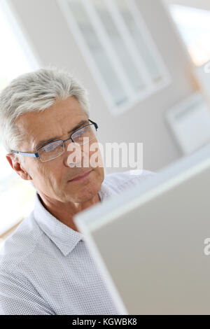 Senior man connected on desktop computer Stock Photo