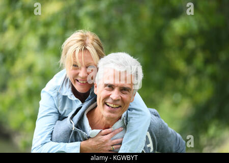 Senior man giving piggyback ride to his wife Stock Photo