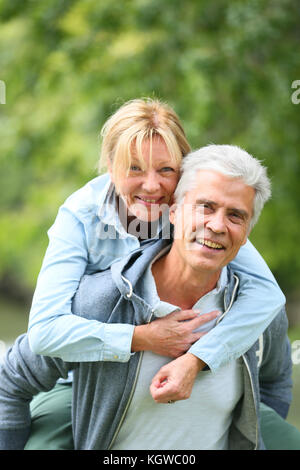 Senior man giving piggyback ride to his wife Stock Photo