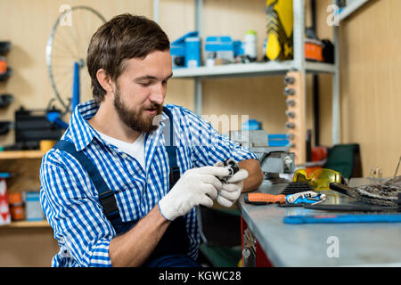 Young master of bicycle repair in uniform and gloves doing his work Stock Photo