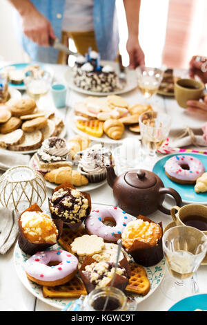 Homemade pastry and drinks on served table with man cutting cake on background Stock Photo