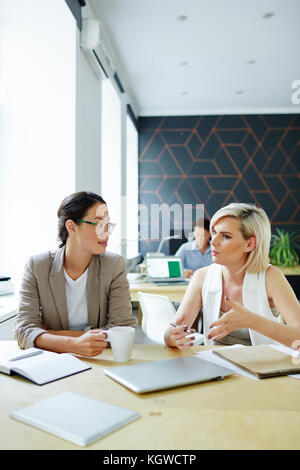 Two colleagues discussing working moments during coffee break in office Stock Photo