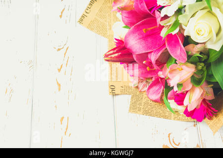 A bouquet of flowers from a lily, gerbera, white roses and alstroemeria on a white wooden table. A holiday, a gift Stock Photo