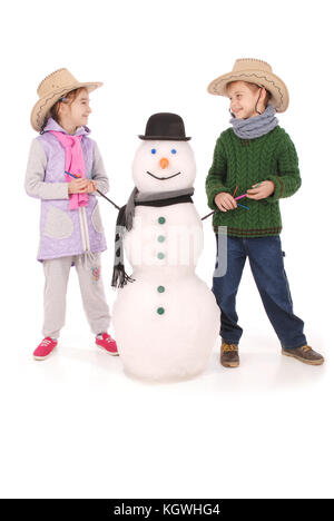 Cute boy and girl with snowman with scarf and hat on white background Stock Photo