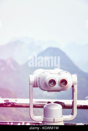Vintage toned picture of tourist binoculars pointing at mountains, selective focus, copy space above. Stock Photo