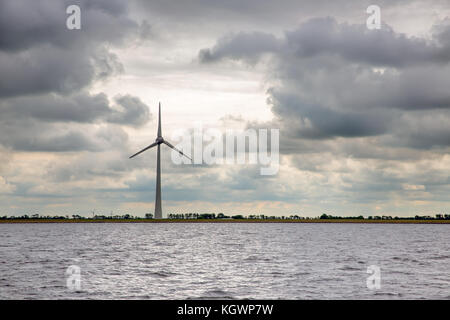 Wind turbine at Dutch coast with threatening dark sky Stock Photo