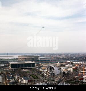 Panoramic aerial view facing north-northwest taken from the New York State Pavilion observation tower at the New York World's Fair, Flushing Meadows-Corona, Queens, New York, May, 1965. An airplane with contrails flies off from LaGuardia Airport at center frame. Seen below are the major landmarks of the fair: the steel globe Unisphere in the foreground, the United States Pavilion building at lower left, and the William A. Shea Municipal Stadium directly behind at midground. In the background is the neighborhood of College Point on the shoreline of Flushing Bay. Stock Photo