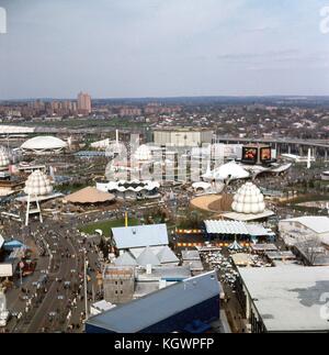 Panoramic aerial view facing northeast from the New York State Pavilion observation tower, at the New York World's Fair in Flushing Meadows-Corona, Queens, New York, May, 1965. A multitude of exhibits are visible: At foreground is the Sweden, Switzerland, and France Pavilions. At left foreground curving away to the center edge is the Avenue of the United Nations South filled with park visitors. Cutting across center at an angle is the Avenue of Africa, and from left to right are the Guinea Pavilion, the Sermons of Science building, the Medo Photo Supply hut, and the Eastman Kodak Pavilion with Stock Photo