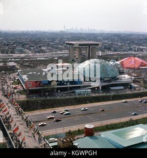 Panoramic view facing west taken from the observation tower of the New York State Pavilion at the New York World's Fair in Flushing Meadows-Corona, Queens, New York, May, 1965. The Manhattan skyline is seen in the distant background. At center running north-south is 111th Street, with the Port Authority Heliport building (Terrace on The Park) at the intersection with 52nd Avenue. At center frame from left to right are the Transportation and Travel Pavilion building with adjoining Moon Dome, and the Chrysler Autofare Pavilion. In the foreground cars travel north and south along the Grand Centra Stock Photo