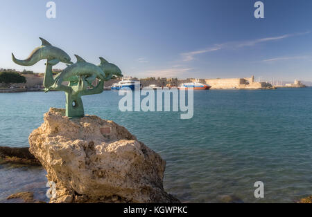 A sculpture depicting four dolphins standing at a harbor on the island of Rhodes Stock Photo