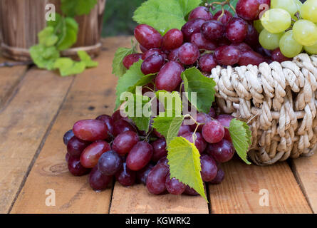 Closeup of red grapes on a wooden surfaceleaves Stock Photo