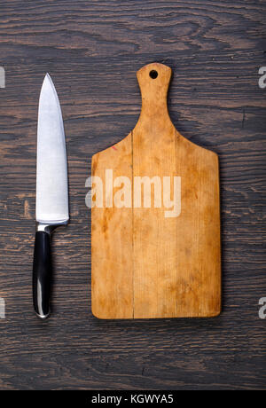 Empty chopping board with a knife on a distressed grunge wooden table in a rustic kitchen, Stock Photo