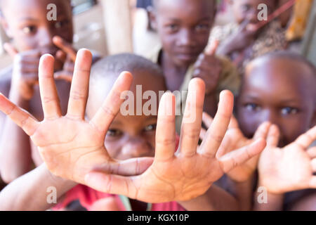 A bunch of random Ugandan children on the street laughing, smiling, waving and having fun in front of the camera. Stock Photo