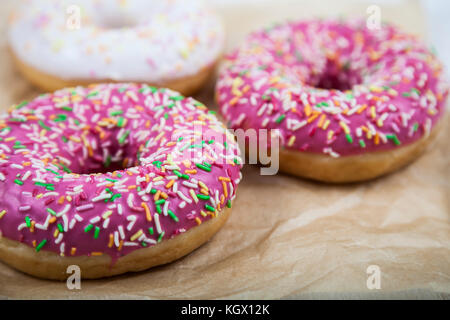 Three donuts on paper. Delicious dessert. Stock Photo