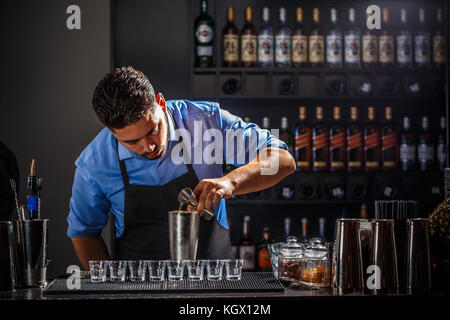 The hands of a professional bartender pour red syrup into a measuring glass  of jigger, next to a metal tool for preparing and stirring alcoholic cockt  Stock Photo - Alamy