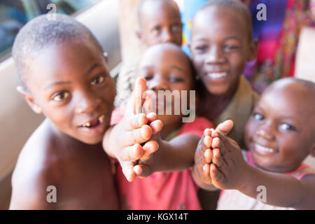 A bunch of random Ugandan children on the street laughing, smiling, waving and having fun in front of the camera. Stock Photo