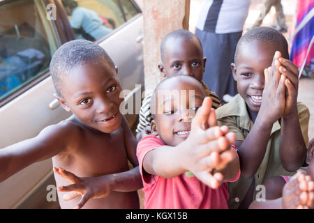 A bunch of random Ugandan children on the street laughing, smiling, waving and having fun in front of the camera. Stock Photo