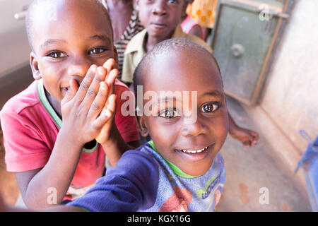 A bunch of random Ugandan children on the street laughing, smiling, waving and having fun in front of the camera. Stock Photo