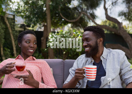Happy couple having lemon tea and black coffee in garden Stock Photo
