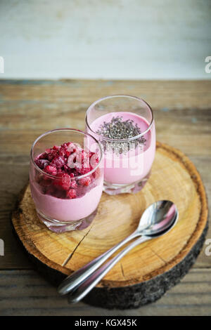 Chia and frozen raspberies cottage cheese breakfast in two small transparent glasses