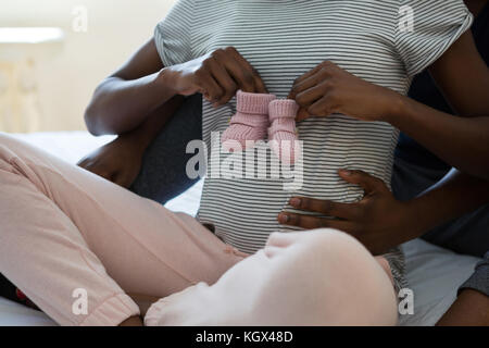 Couple holding baby socks in bedroom at home Stock Photo