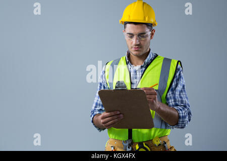 Male architect writing on clipboard against white background Stock Photo