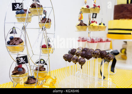 Assortment of birthday party cakes in yellow and black color, pirate theme, for boy. Focus cakepops Stock Photo
