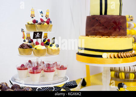 Birthday party cupcakes, pudding in a cup, and birthday cake, in yellow and black pirate theme for boy Stock Photo