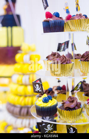 Cupcakes on stand in yellow and black colors, pirate theme for kids birthday party Stock Photo