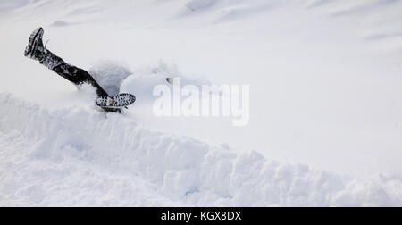 Man is falling headfirst into deep snow. Concept of winterly slippery conditions. Stock Photo