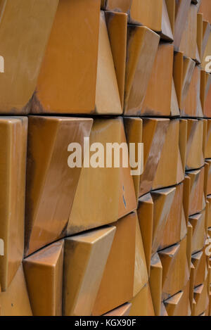 Portrait format shot of decorative exterior wall with weather-worn and stained yellow and orange bricks in city Stock Photo
