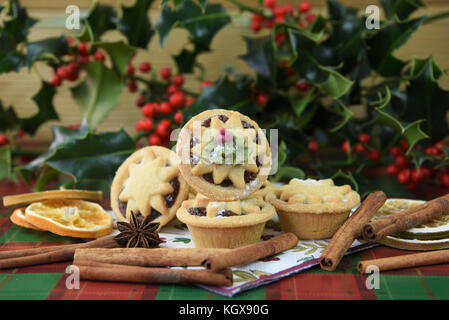 Christmas food photography image with traditional iced pastry fruit mince pies and star top with real fresh green holly and red berries in background Stock Photo