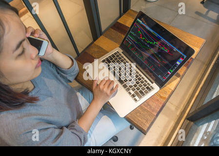 Young investor using phone and checking stock market Stock Photo