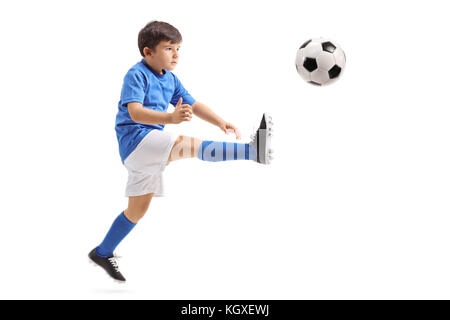 Little soccer player kicking a football in mid-air isolated on white background Stock Photo