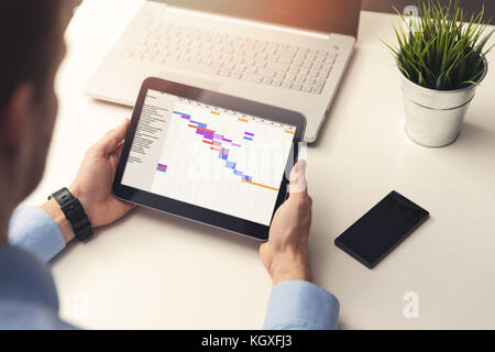 project manager looking at gantt chart on digital tablet in office Stock Photo