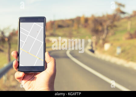 Hand holding smartphone with gps map on autumn outdoor background as traveling or backpacking concept Stock Photo